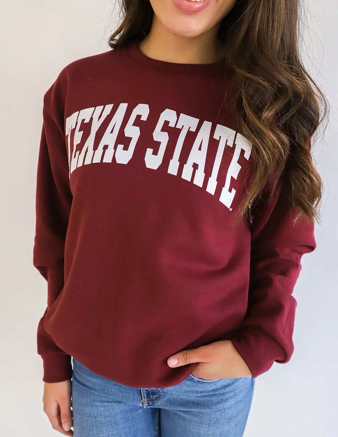 Person wearing a maroon 'Texas State' sweatshirt against a plain background