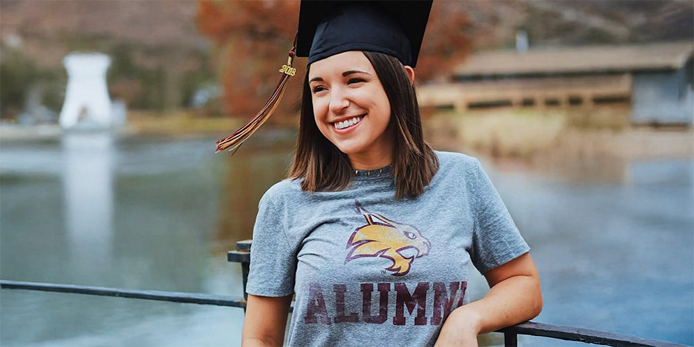 girl wearing a Texas State alumni tshirt and a graduation cap