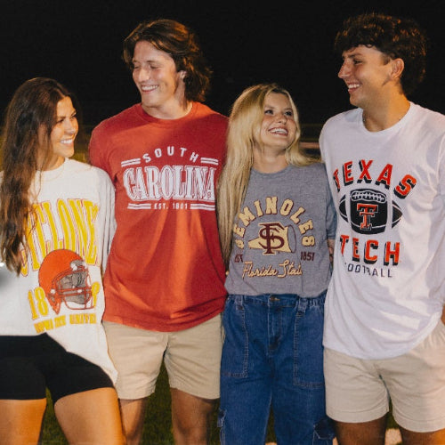 Group of people wearing various casual outfits with text 'Game Day 2024' and 'Shop Now' on a sports field background.