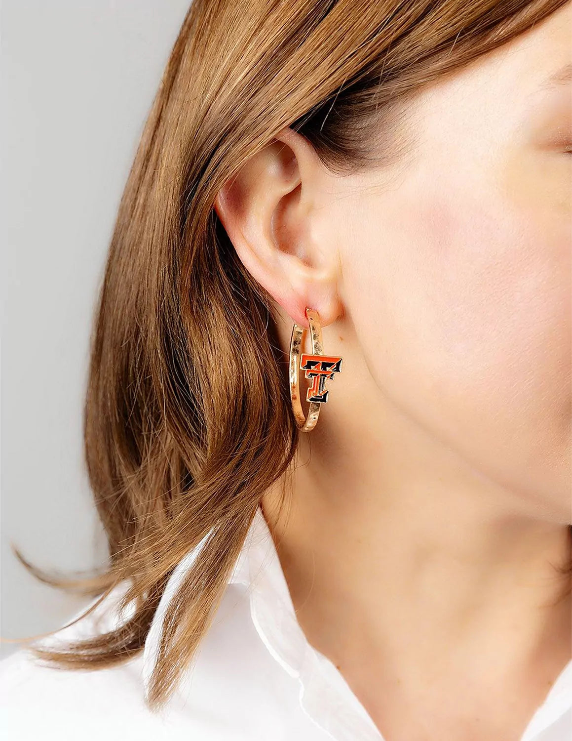 Texas Tech University model wearing TTU gold hoop earrings.