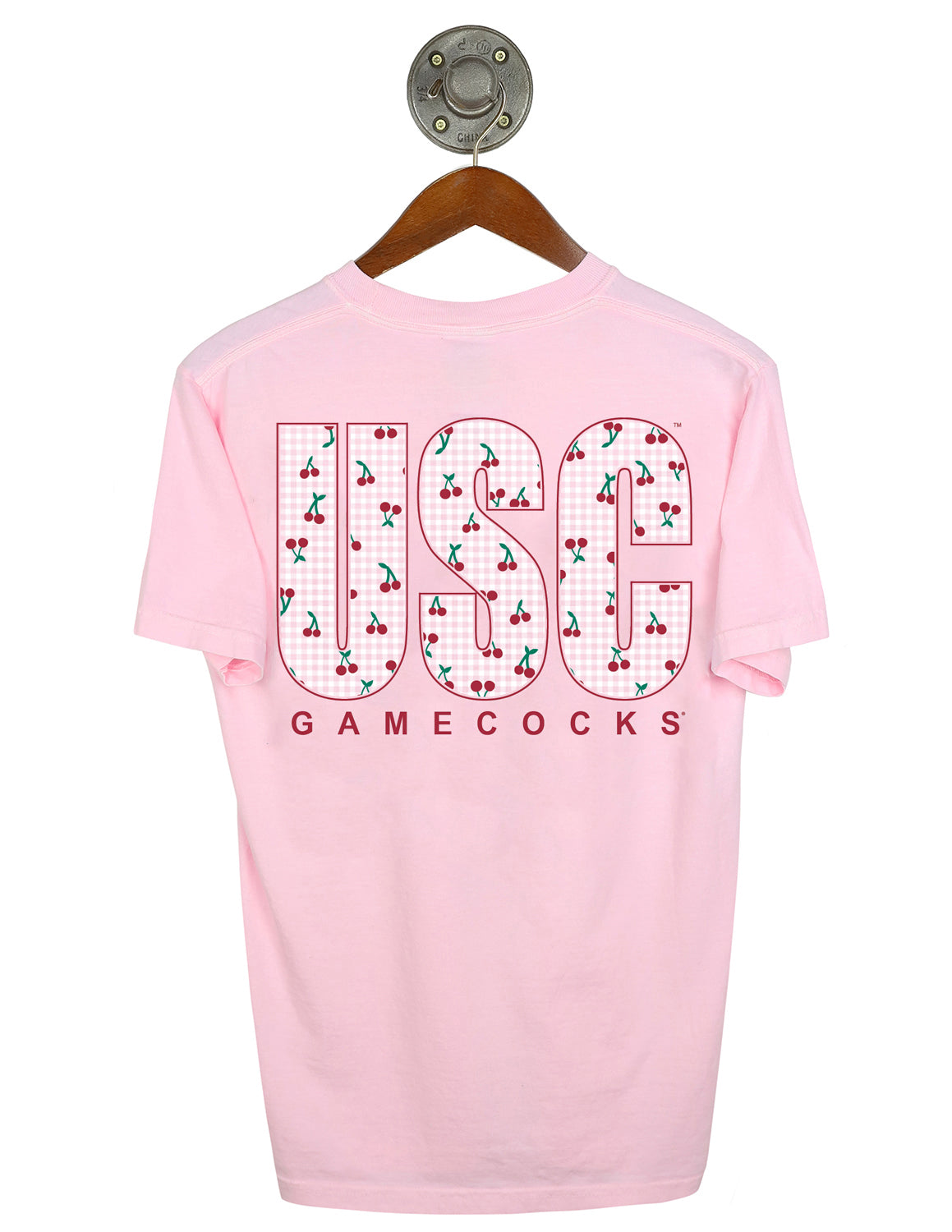 Back-view of light pink University of South Carolina Comfort Colors t-shirt that features large "USC" block letters filled with a red cherry and white gingham pattern with red lettering underneath.
